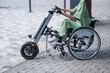 © Михаил Решетников - A woman controls a wheelchair using a special manual device. Close-up of female hands on electric handbike.