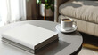 © Elnare - A white book mockup on a coffee table with a cup of coffee and a couch in the background.