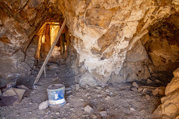 An abandoned mine tunnel inside Aguereberry Camp in Death Valley, California, showcasing remnants of old mining equipment and rugged rock formations in a historic desert landscape.