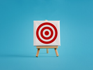 Poster - Red target on white canvas standing on easel over blue background