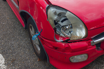 Broken car red bumper and light after a collision crash in street