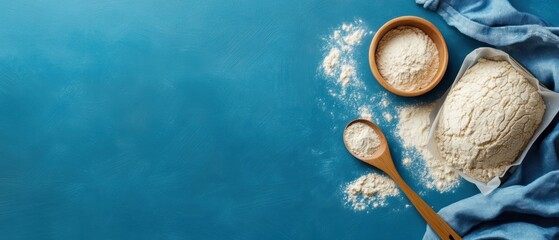 Flat lay of various types of flour with a wooden spoon and bowl on a blue background, perfect for baking and cooking themes.