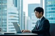© Jiraphat - Focused businessman working on laptop in modern office with city view. Professional environment, corporate lifestyle.