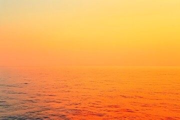 Wall Mural - A serene ocean view at sunset, showcasing vibrant orange and yellow hues across the water.