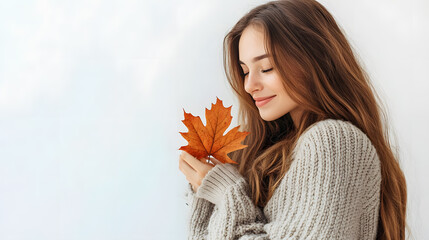 Beautiful smiling woman wearing jeans and sweater, holding a maple leaf in her hand isolated on white