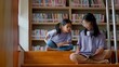 © FAMILY STOCK - Two Asian siblings sit on the steps of a library, intently reading a book together, and share a moment of discovery and curiosity.