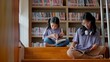 © FAMILY STOCK - Two Asian siblings sit on the steps of a library, intently reading a book together, and share a moment of discovery and curiosity.
