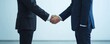 © Jenjira - Two business professionals shake hands in a formal setting, symbolizing partnership and agreement in a corporate environment.