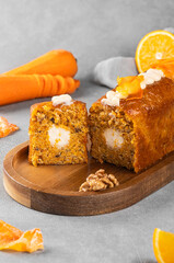 delicious and fluffy carrot cake with cream filling, walnuts and carrot chips on a wooden board. Homemade baking concept