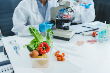 two asian women in a lab work on food research, using a microscope, petri dish, and test tubes fille