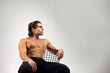 © Alex Vog - Perfect young man muscular fashion model with sexy bare torso sitting on chair, confident looking away. Studio snap shot of sporty strong muscle guy with muscle abs press on white. Copy ad text space