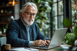© mattegg - Senior Man Working on Laptop in Cafe