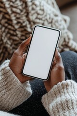 African American woman holding cell phone with mockup white blank display, empty screen for app ads inside house. Concept of mobile applications technology, over shoulder close up.