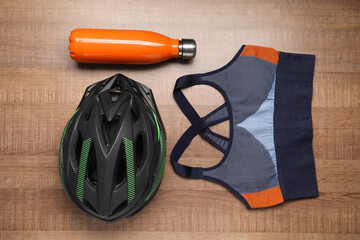 Wall Mural - Bicycle helmet, sportive bra and thermo bottle on wooden background, flat lay