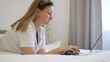 © Traveler0205 - Woman works on a laptop while lying in bed, typing on laptop keyboard. The scene shows productivity and comfort with laptop use in a relaxed setting. Ideal for illustrating work-from-home concepts.