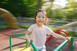 © Ilshat - Five Years Old Cheerful Asian Girl Smiling While Riding Playground Merry-Go-Round