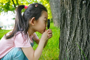 child girl exploring nature with magnifying glass