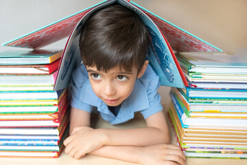 Happy cute boy in glasses with many books enjoys learning isolated on white background. Amblyopia, strabismus. Learning concept