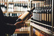 © Ilshat - Faceless Person Holds Taking from Shelf Bottle of Wine in Store, Close up