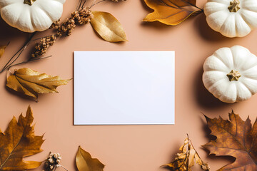 Photo of a blank white card mockup on a pastel BROWN background with golden leaves and pumpkin decoration, in a flat lay. Top view