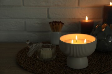 Wall Mural - Burning candles and decor on table near white brick wall. Space for text