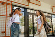 © Forewer - Multiethnic elementary middle school girls gen Alpha pupils classmates with backpack in casual clothes are hugging embracing each other standing outdoors. Part of a series