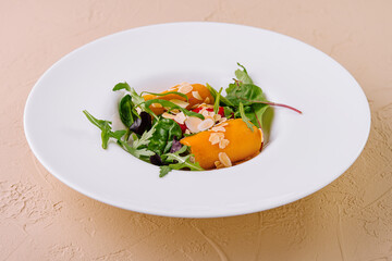 Salad with yellow bell pepper, almond petals and herbs on white plate