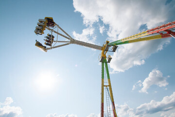 Colorful amusement ride at a fair against a blue cloudy sky.