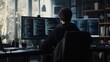 © panumas - A man is sitting in front of two computer monitors, one of which is displaying a code. Concept of focus and concentration as the man works on his computer