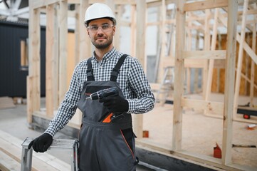 Wall Mural - Portrait of a young carpenter worker in a helmet at the construction site of modular houses