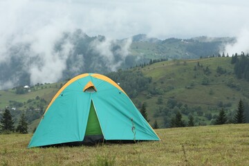 Poster - Camping tent on green grass in mountains