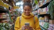 © Charoen - A woman is smiling while looking at her cell phone in a grocery store