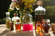 © New Africa - Different tinctures in bottles and ingredients on wooden table outdoors