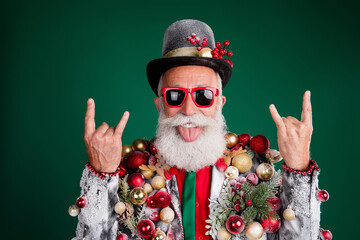 Canvas Print - Photo of serious old cool man rock symbol tongue out dressed decor balls baubles on jacket sunglass hat isolated on green color background