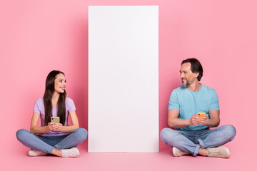 Wall Mural - Full body photo of two positive partners sit floor look empty space huge phone isolated on pink color background