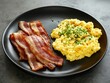 © Spencer - Plate of scrambled eggs garnished with chives and crispy bacon slices on a black dish. Keto. Carnivore diet.