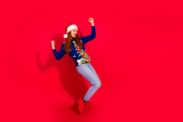 Poster - Full length photo of lucky positive girl wear unly print sweater santa hat celebrating xmas empty space isolated red color background