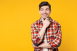 © ViDi Studio - Young smiling happy Caucasian man he wears red checkered shirt casual clothes put hand prop up on chin, lost in thought and conjectures isolated on plain yellow orange background. Lifestyle concept.