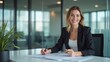 © PinoyCapture - Professional Woman Smiling in a Black Suit Jacket Over a White Shirt with a Blurred Corporate Office background, Possibly Reviewing or signing a Documents.