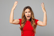 © ViDi Studio - Young sad mad angry furious indignant unhappy woman she wear red t-shirt casual clothes look camera scream shout spread hands isolated on plain pastel light grey background studio. Lifestyle concept.