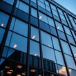 © Karn AS Images - Closeup of a contemporary building exterior with large glass windows and sleek metal framing, reflecting the sky and surrounding urban environment