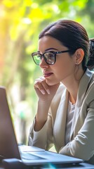 Wall Mural - Young woman in glasses looking intently at her laptop.