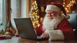 © Glce - happy smilling Santa Claus sits at the table with laptop