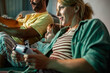 © Marko Geber - Young family playing video games at night on the couch in the living room at home