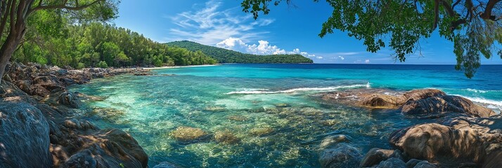 Panoramic view of a beautiful tropical beach with clear blue waters, lush greenery, and rocky shoreline adorning the coast.