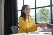 © amnaj - Successful businesswoman confidently seals a deal with a client in a bright office, smiling and shaking hands