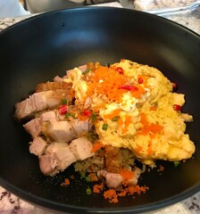 Crispy Pork Belly with Scrambled Eggs and Rice Topped with Tobiko in Black Bowl