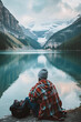 © Fabio - Traveler resting by a lake with mountains in the background