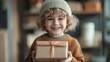 © Phirakhup - A cheerful child in a cozy setting holds a beautifully wrapped gift, radiating joy and excitement in a warm atmosphere.