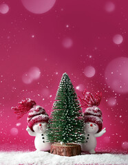 Wall Mural - Two little snowmen in caps with Christmas tree on snow in the winter. Background with a funny snowmen. Christmas card.